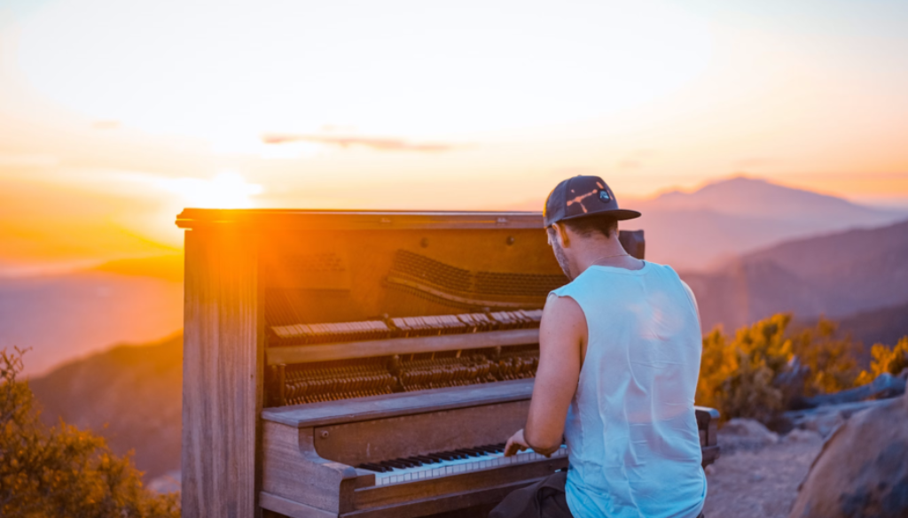 man playing piano outside at sunrise