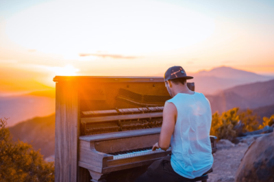man playing piano outside at sunrise